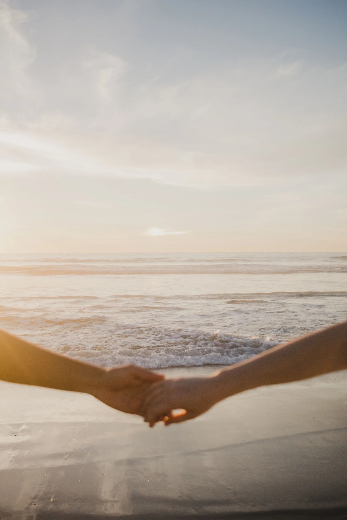 Two people holding hands at the shoreline