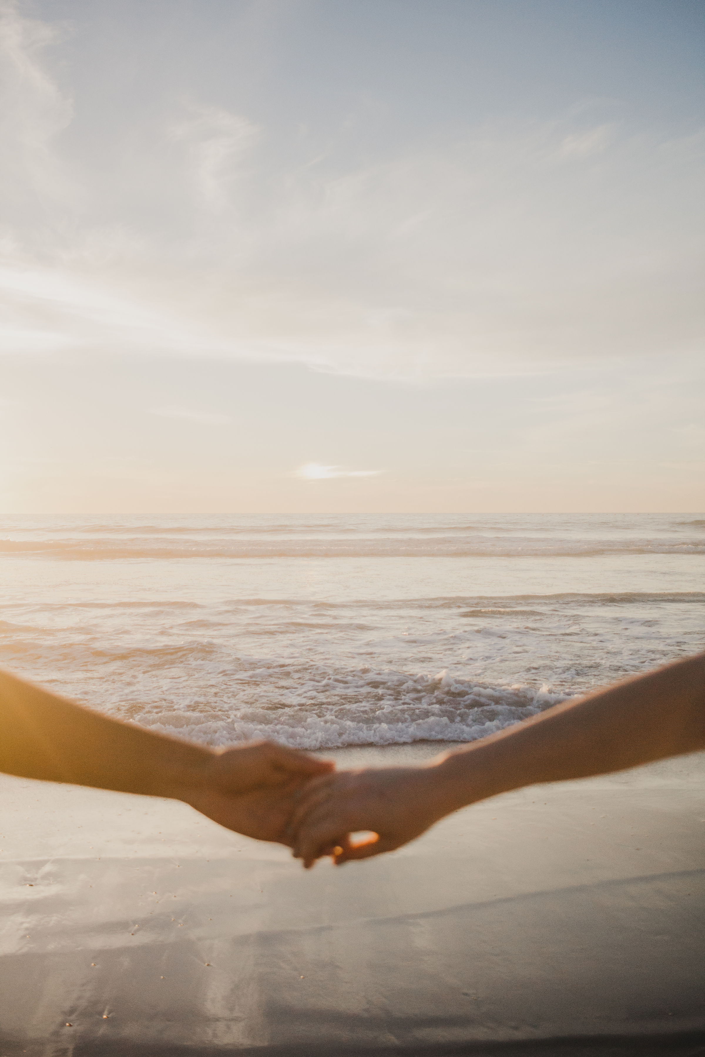 Two people holding hands at the shoreline